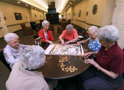 Group of elderly women working on a large jigsaw puzzle together